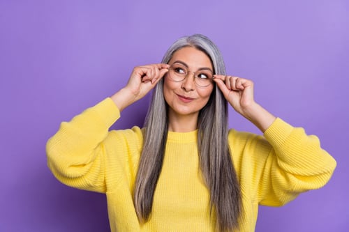 Femme debout et pensive en tenant les montures de ses lunettes