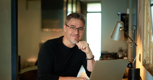 Statut social mandataire immobilier - Homme souriant au bureau tout en regardant l'objectif