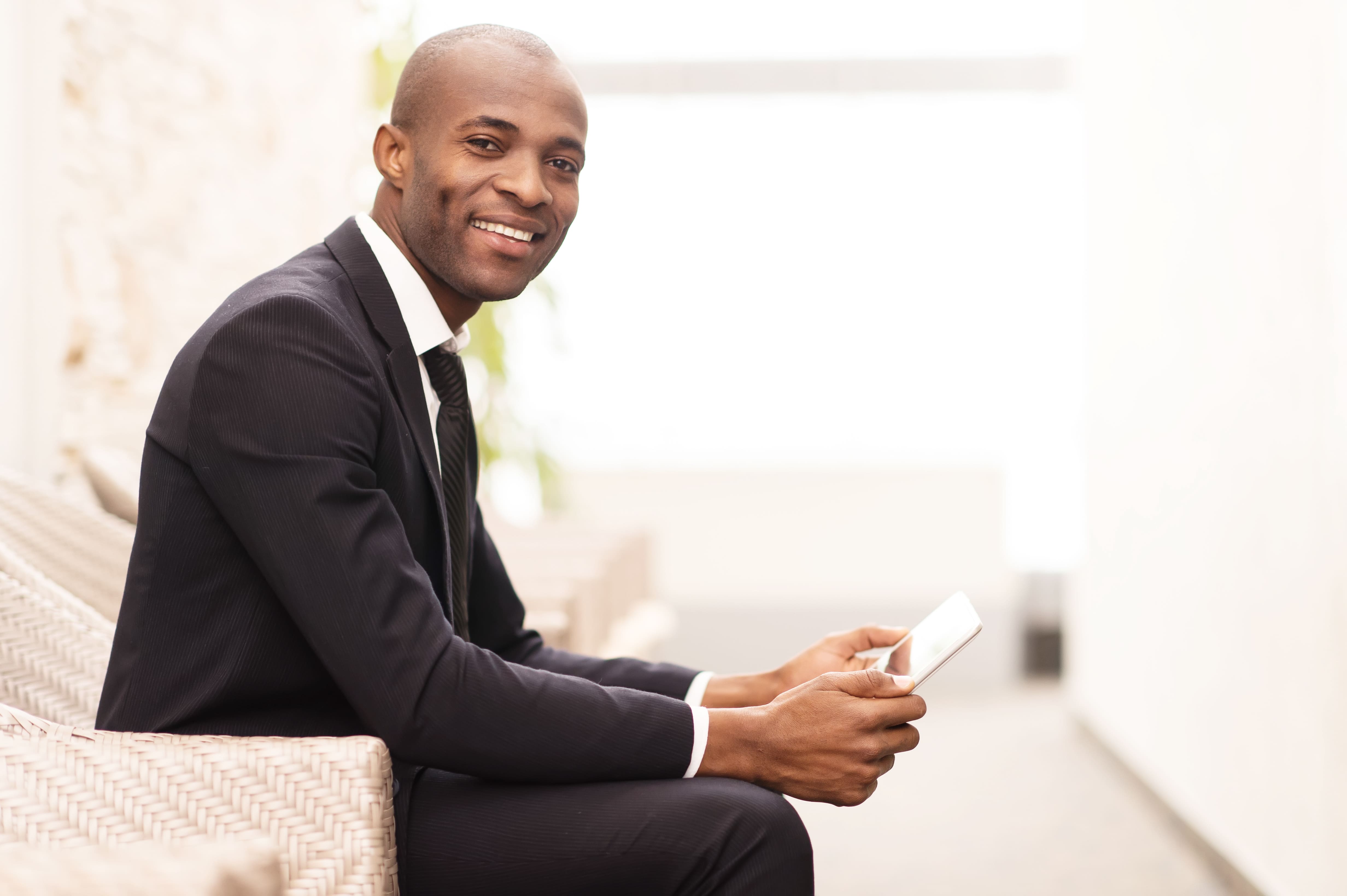 Homme assis avec sa tablette dans les mains et souriant