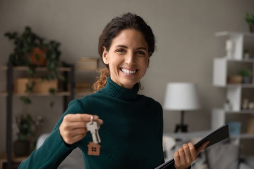 Negociateur immobilier souriant en tenant une paire de clés d'un bien immobilier