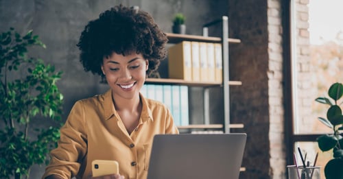 Statut entreprise mandataire immobilier - Femme au bureau souriant en regardant son telephone