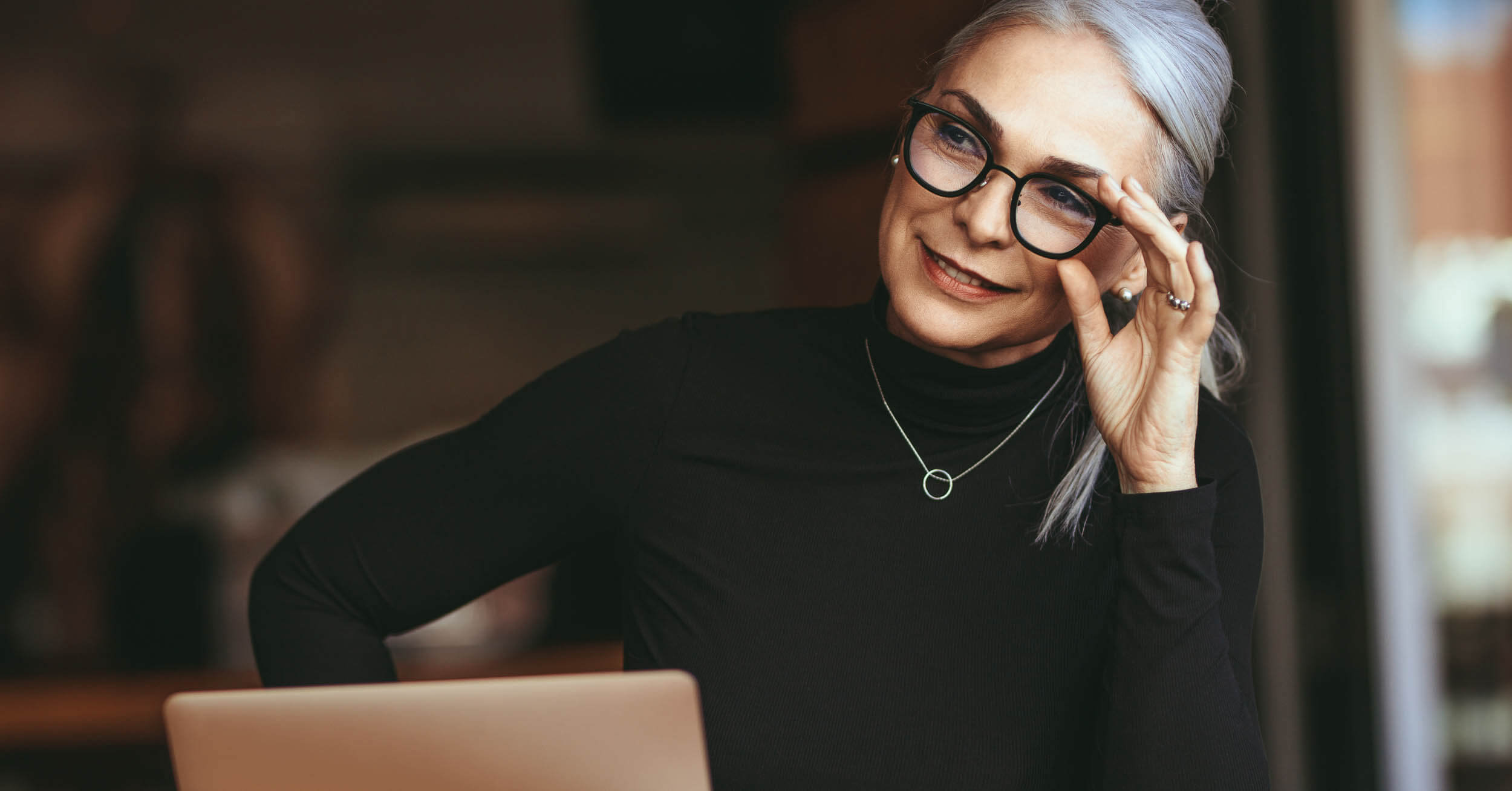 Mandataire immobilier independant - Femme regardant devant elle en tenant ses lunettes au visage