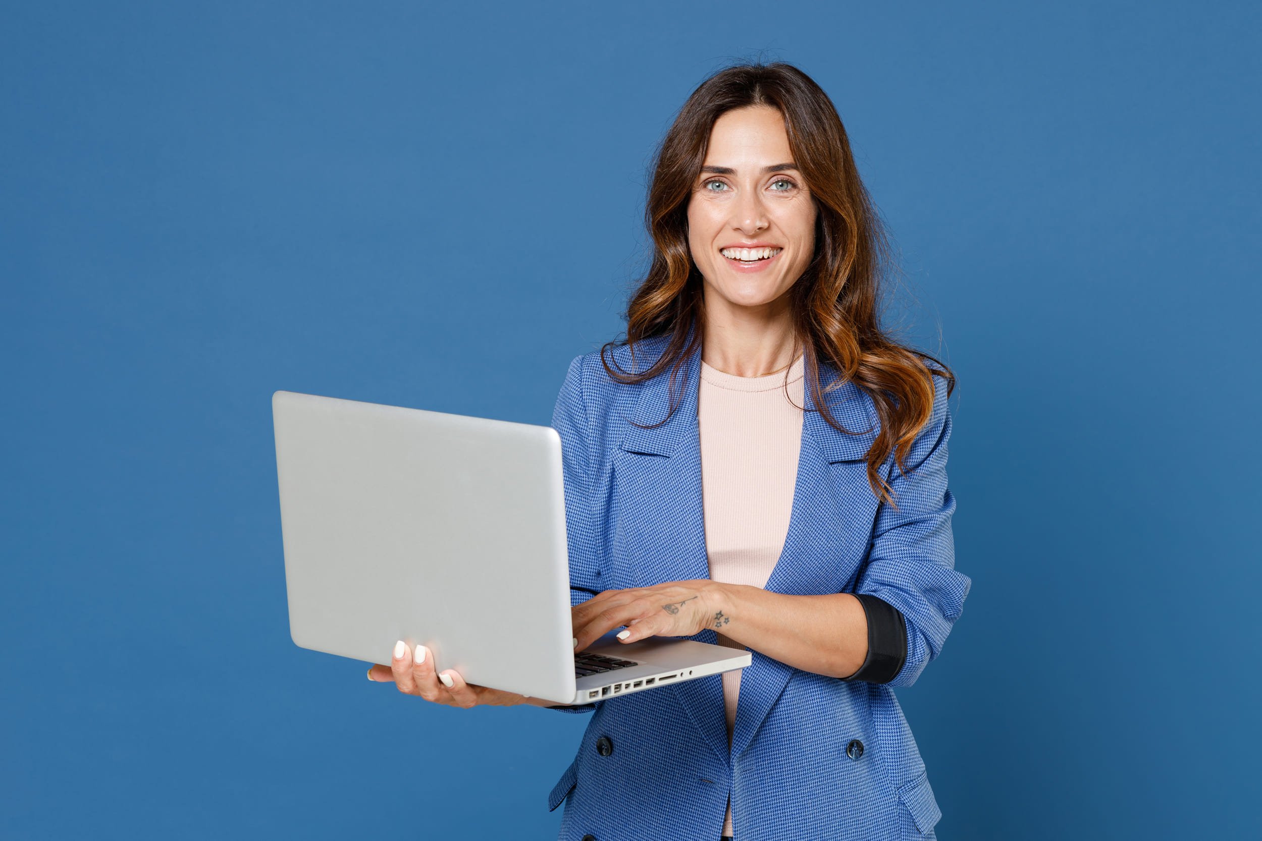 Femme debout avec le sourire et tenant son ordinateur portable ouvert